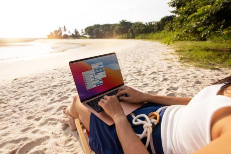 Mujer trabajando en la playa con un portátil 