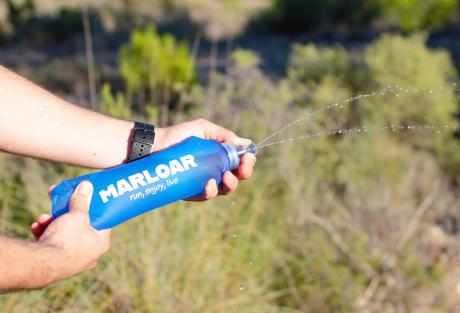 Botella de agua flexible MARLOAR sostenida con las manos al aire libre
