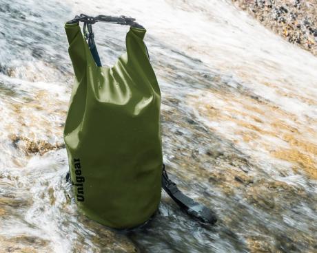 Bolsa estanca Unigear verde junto a unas rocas con agua
