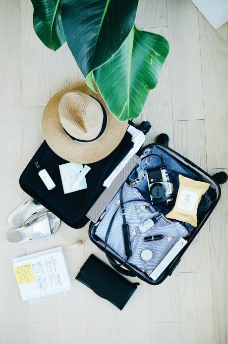 Maleta abierta con ropa, cámara y accesorios preparados para viajar