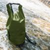 Bolsa estanca Unigear verde junto a unas rocas con agua