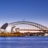 Jørn Utzon's Sydney Opera House, and the Harbour Bridge, two of Sydney's most famous landmarks, taken at late dusk. The Sydney Opera House is one of the most iconic buildings built in the 20th century (1973) and is UNESC